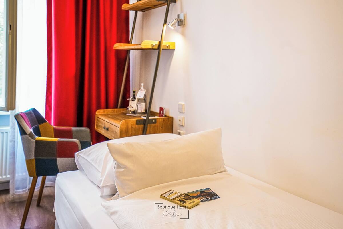 Ein Hotelzimmer mit Bett, Stuhl, Nachttisch und Lampe.