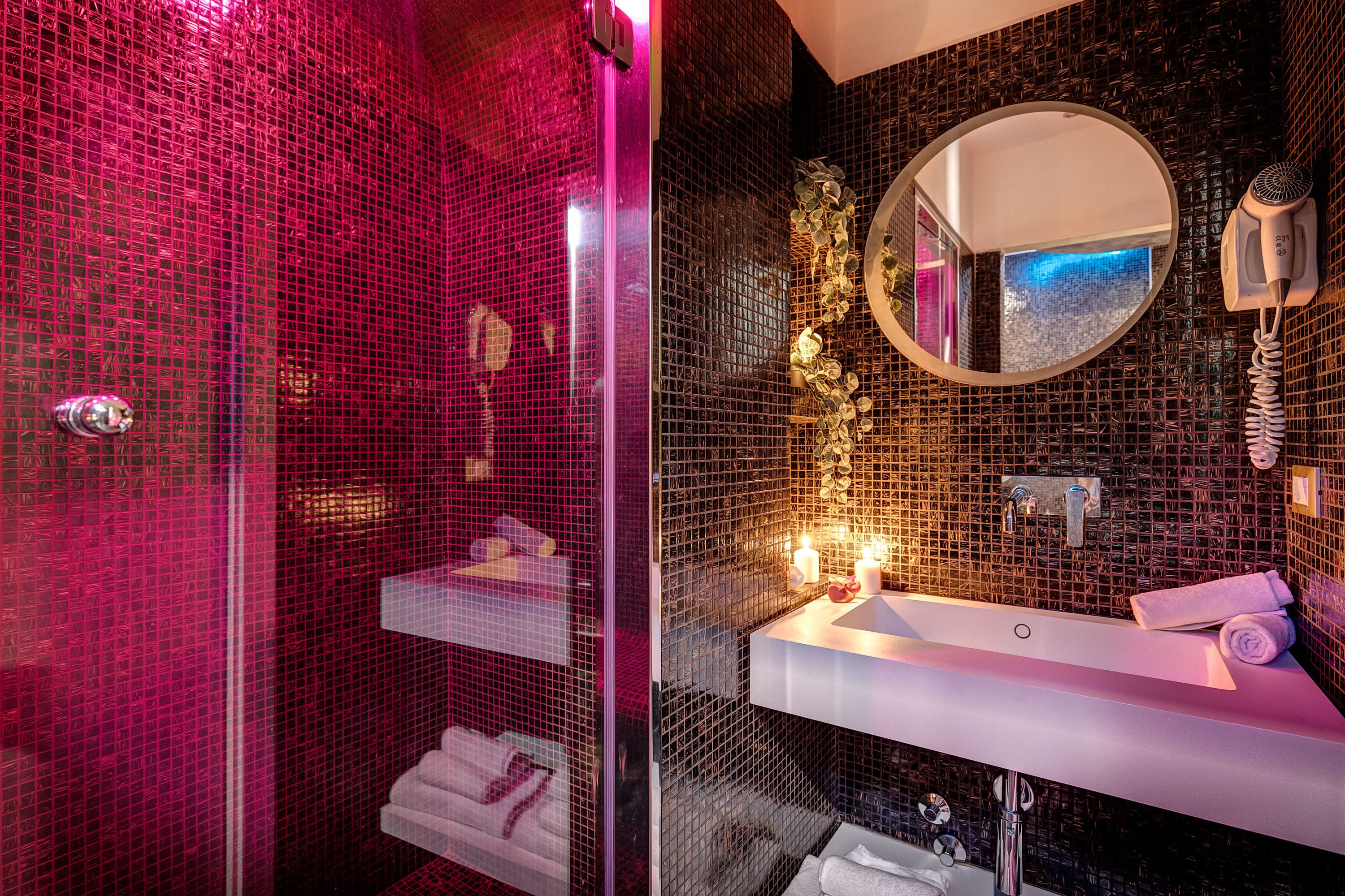 Moderni kylpyhuone, jossa on lasiseinällä varustettu suihku, peilillä varustettu allastaso ja lämmitettävä pyyhekoukku.