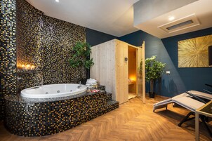 A modern bathroom with a mosaic tile wall, a freestanding bathtub, and a wooden door leading to a shower area.