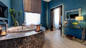 Une salle de bain moderne avec un lavabo recouvert de mosaïques, un grand miroir et une console en verre agrémentée d’objets décoratifs.