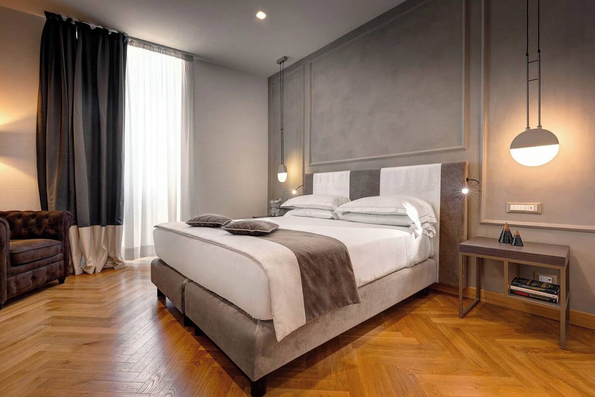 A modern bedroom with a large bed, a side table, and a sofa.