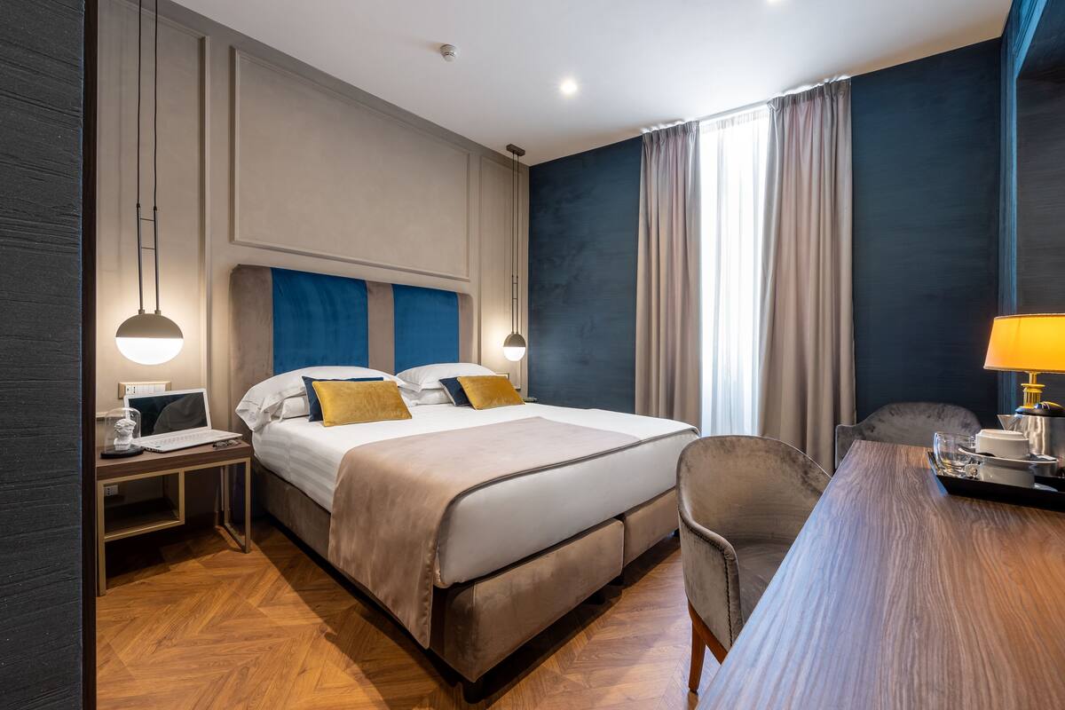 A hotel room with a large bed, bedside tables, a desk, and a chair.