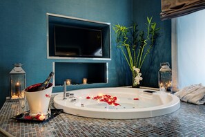 A modern bathroom with a large bathtub, a mounted TV, and decorative plants. - Dharma Style Hotel & Spa (Rome)