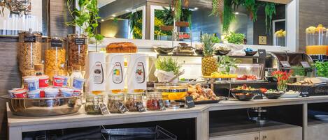 Un buffet proposant une variété de plats, notamment des fruits, des pâtisseries et des condiments.