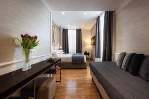 Una camera d'hotel moderna con un letto, una scrivania con un vaso di fiori, una sedia e un comodino.