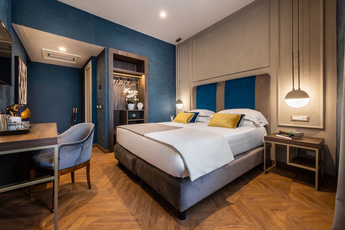 A modern bedroom with a bed, bedside tables, a desk, and a chair.