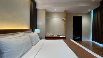 Una habitación de hotel con una cama grande, una mesita de noche con lámpara, un armario y una puerta.