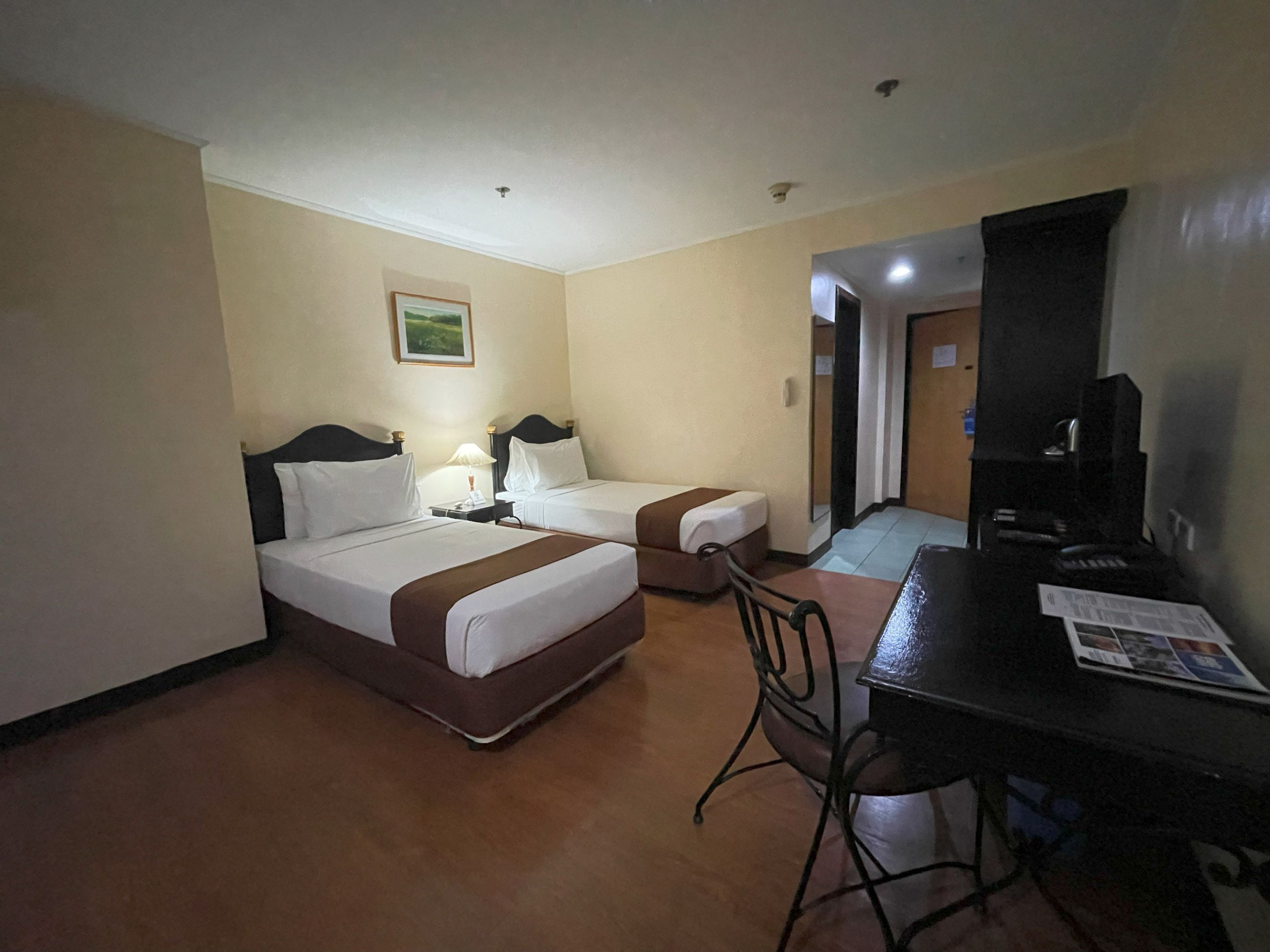 Una habitación de hotel con dos camas, un escritorio, una silla y un televisor.