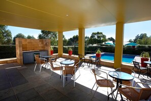 Un área de patio al aire libre con piscina, mobiliario y una cocina.
