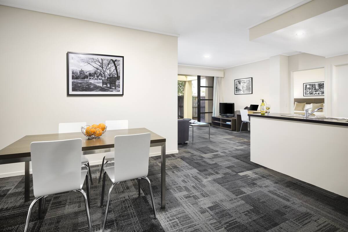 A modern hotel room with a dining area, a kitchen, and a living space.