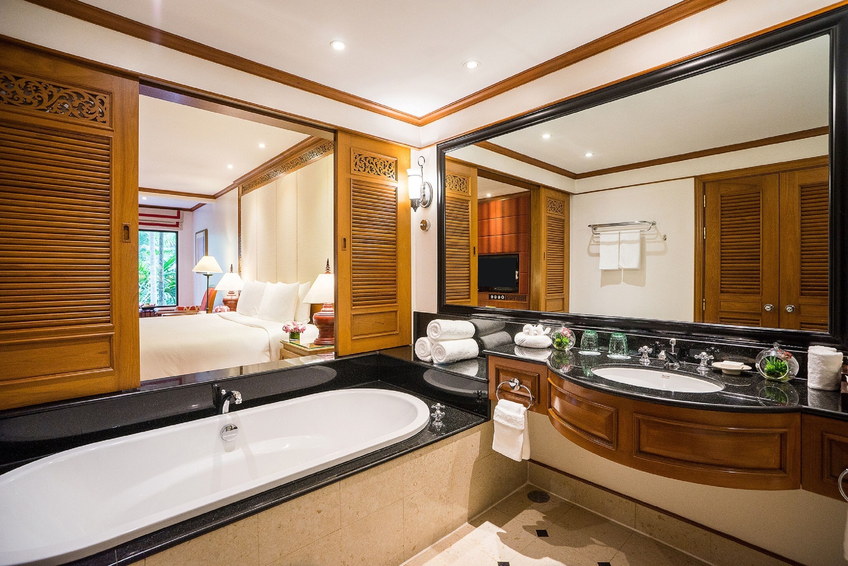 A spacious bathroom with a large bathtub, two sinks, and a large mirror.