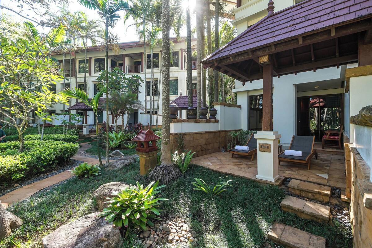 A courtyard with a pool, lounge chairs, and a covered seating area.