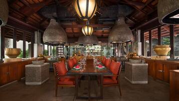 A spacious dining area with a long table, multiple chairs, and hanging light fixtures.