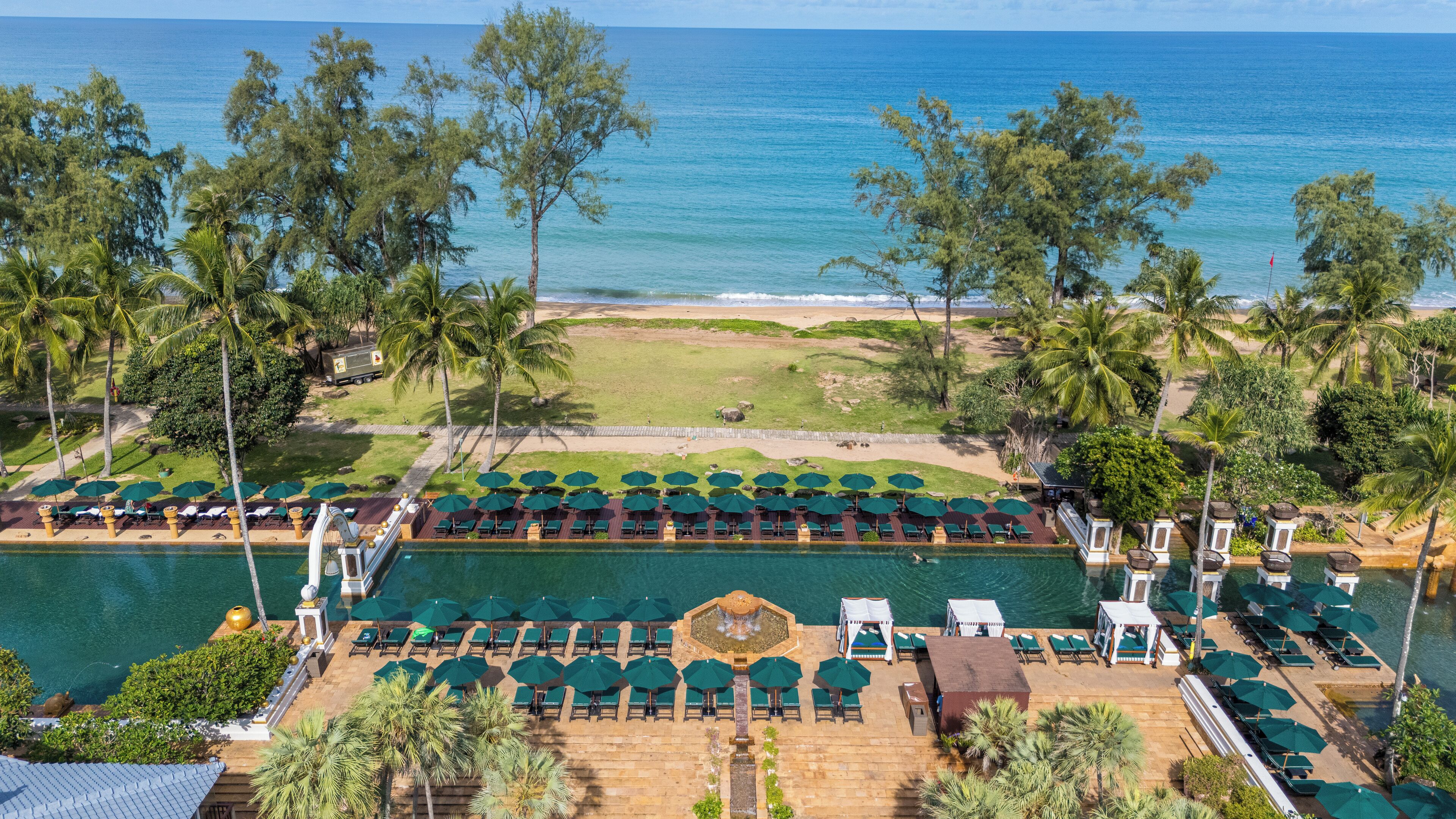 Een resort met een zwembad, terrasgedeeltes en uitzicht op het strand.