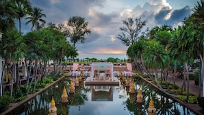 A serene outdoor setting with a reflective pool, a central pavilion, and palm trees. - JW Marriott Phuket Resort & Spa (Mai Khao)