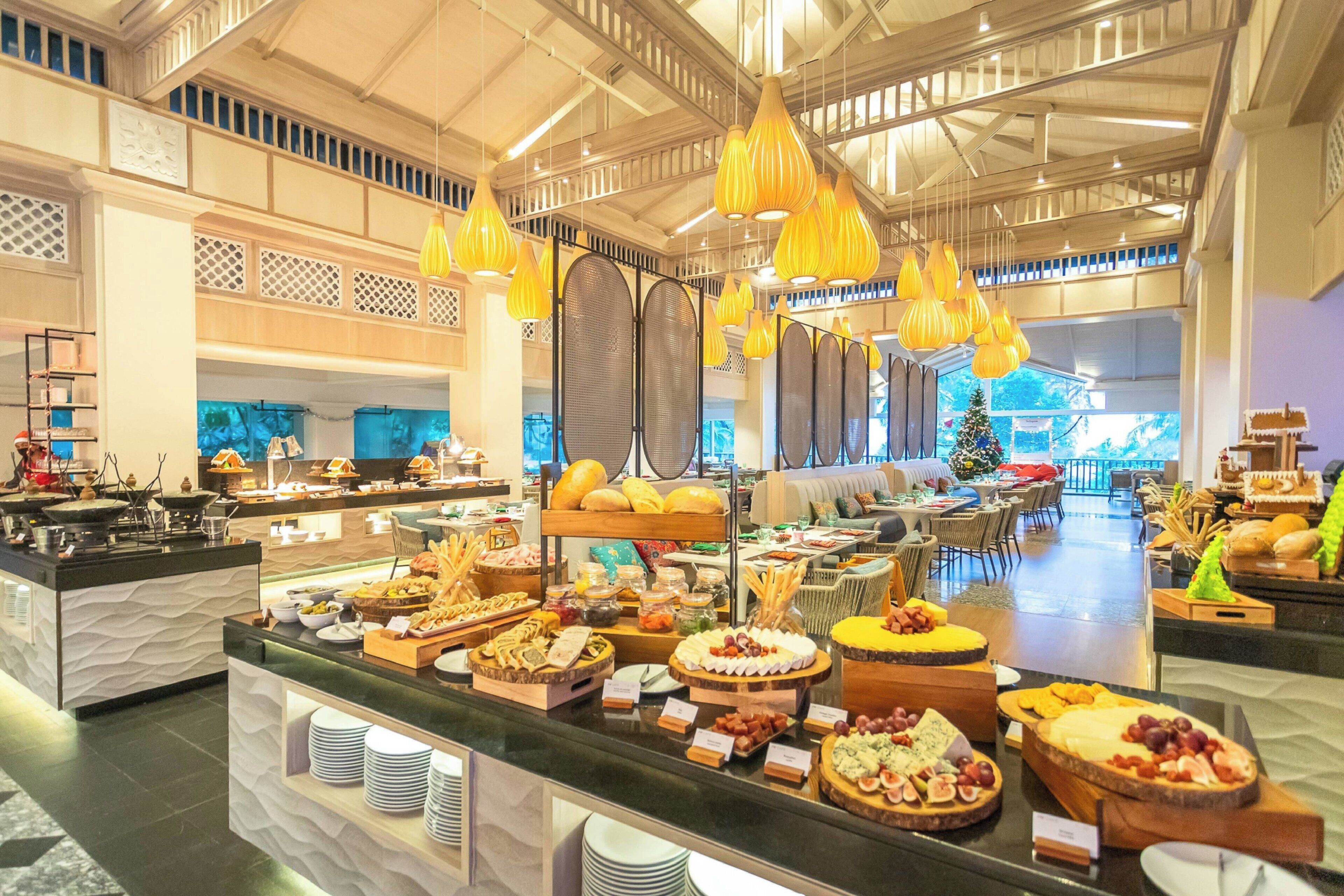 A buffet area with various food items and a Christmas tree in the background.