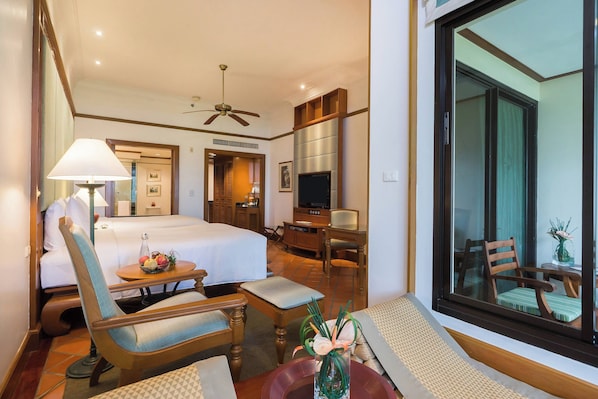 A hotel room with a bed, a desk, a television, a chair, and a window with a view of the outside. - JW Marriott Phuket Resort & Spa (Mai Khao)