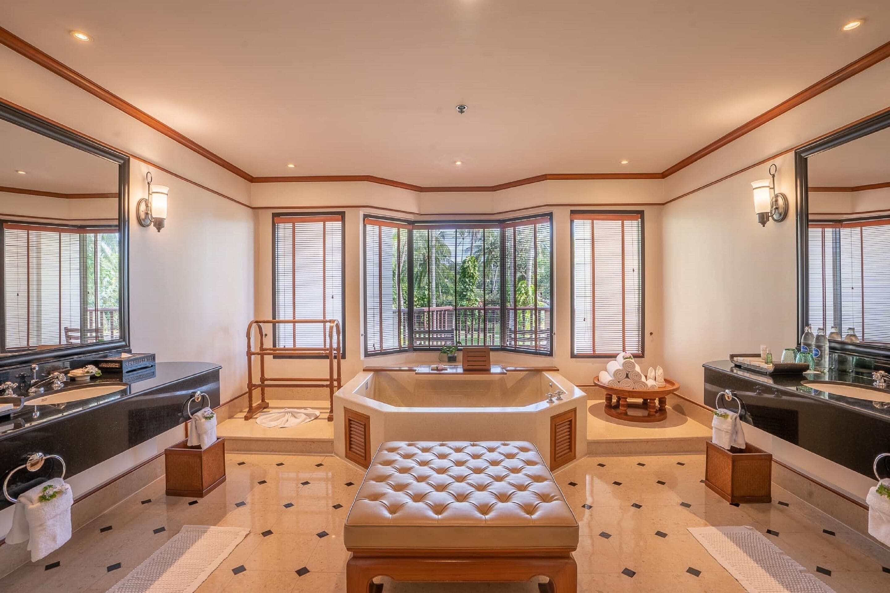 Een luxe badkamer met een ruim bad, dubbele wastafels en een zithoek.
