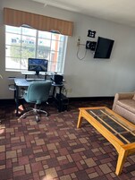 A room with a desk, computer, chair, and a sofa.