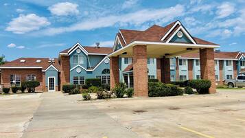 A hotel with multiple buildings, a parking lot, and a clear sky.