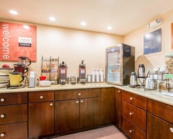 Zona de desayuno de hotel con máquinas de café, un refrigerador y una estación para café.