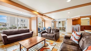 A spacious living area with leather sofas, a wooden coffee table, and a large window offering a city view. - Comfort Inn & Suites Salinas City Center Area (Salinas)