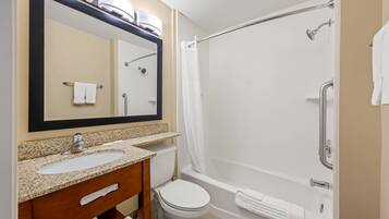 A bathroom with a sink, mirror, toilet, and a shower with a curtain.