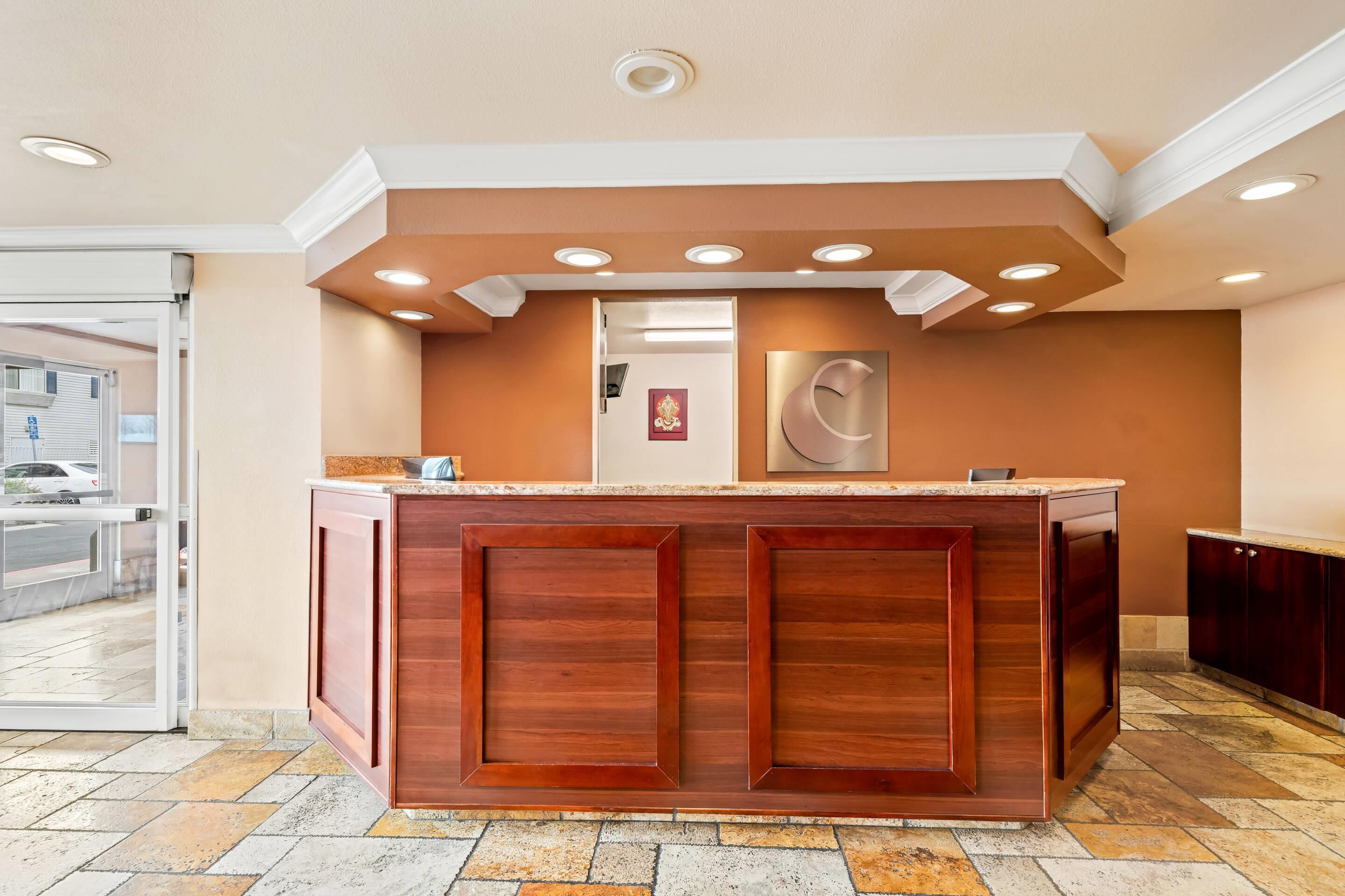 A reception area with a wooden reception desk, recessed lighting, and a view of the outside.