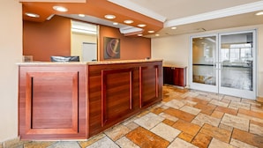 A reception area with a wooden counter, a large mirror, and a glass door leading outside. - Comfort Inn & Suites Salinas City Center Area (Salinas)
