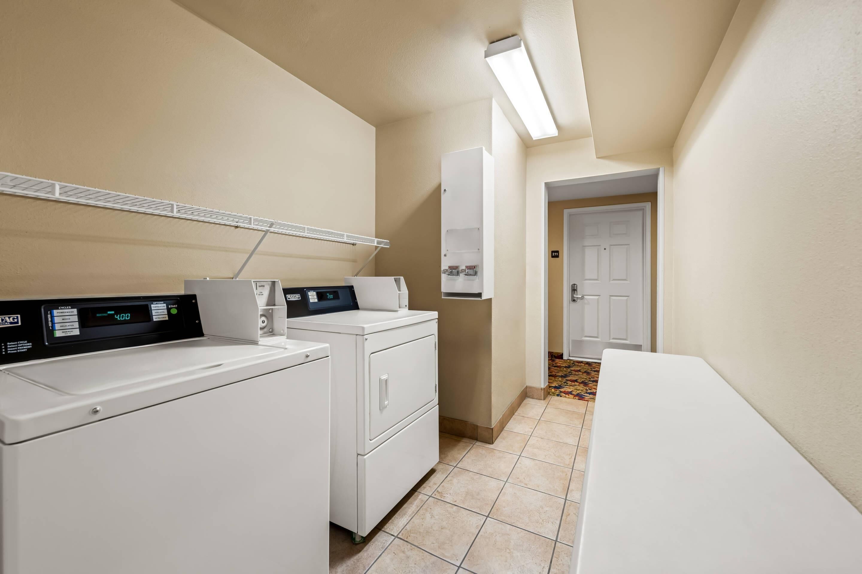 A laundry room with a washing machine, dryer, and a control panel.