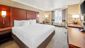 A hotel room with a large bed, bedside tables, a desk with a chair, a TV, and a window with curtains. - Comfort Inn & Suites Salinas City Center Area (Salinas)