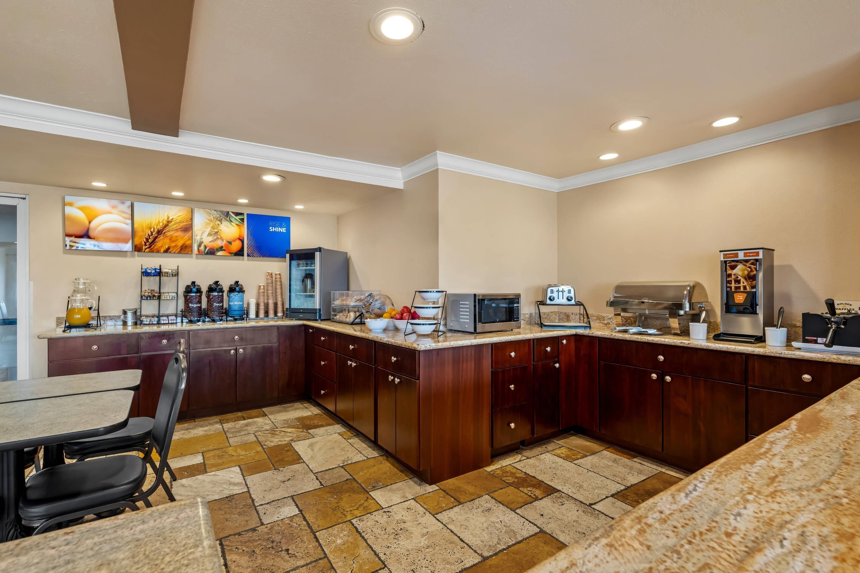 A modern kitchen with a breakfast bar, a microwave, a coffee machine, and a refrigerator.
