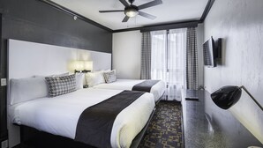 A hotel room with two beds, a ceiling fan, a TV, and a patterned carpet. - Adante Hotel (San Francisco)