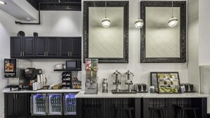 A modern kitchen with dark cabinetry, a white countertop, and two pendant lights. - Adante Hotel (San Francisco)