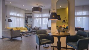 Una sala de estar moderna con un sofá, sillas, una mesa de centro y una mesa redonda con una vela.