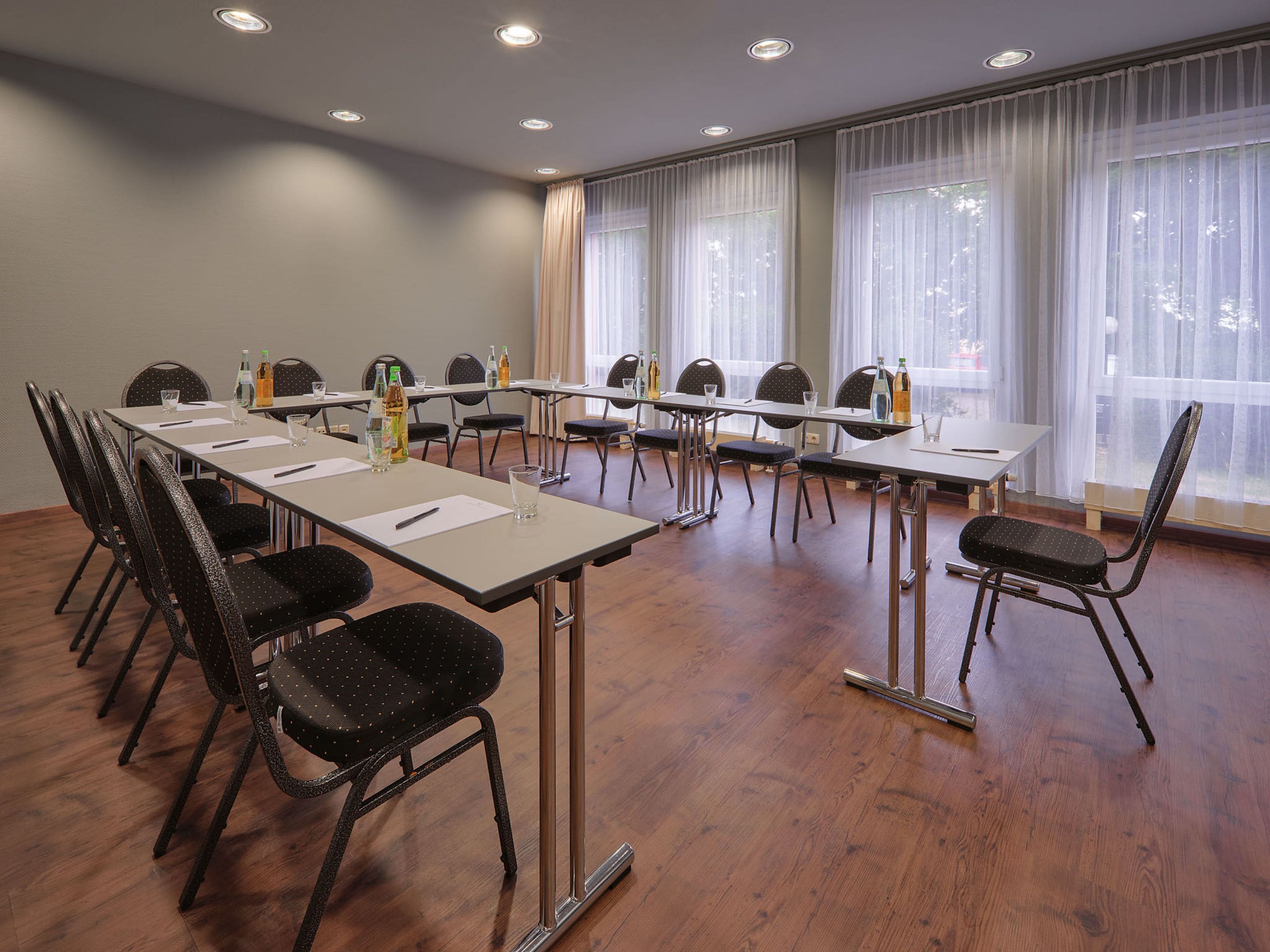 Una sala de conferencias con una larga mesa, sillas y botellas de agua.