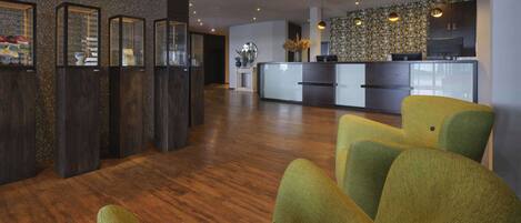 A modern interior with a wooden floor, a reception desk, and a kitchen area.