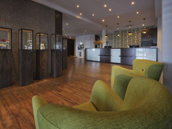 Un interior moderno con suelo de madera, una recepción y una zona de cocina.