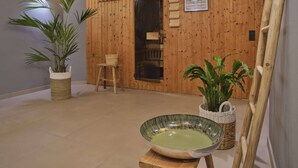 Una habitación con paredes y suelo de madera, una silla de madera, un cuenco grande tejido y dos macetas con plantas.