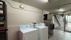 A laundry area with two front-loading washers, a water cooler, and a stairway leading outside. - Motel 6 Richmond, KY – EKU Campus Area (Richmond)