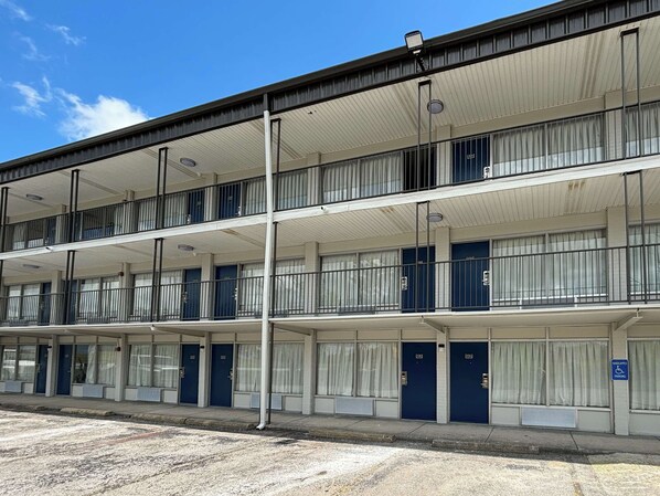 Un motel de varios pisos con una fila de habitaciones en cada planta, que cuenta con balcones y ventanas amplias.