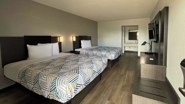 A hotel room with two beds, a TV, and a desk with a mirror. - Motel 6 Richmond, KY – EKU Campus Area (Richmond)
