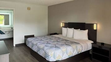 Una habitación de hotel moderna con una cama grande, mesitas de noche y una mesita auxiliar.