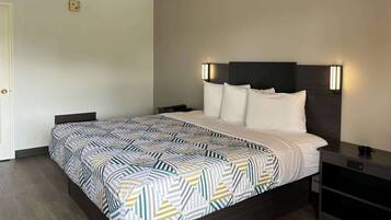 Una habitación de hotel con cama, mesitas de noche y una lámpara fijada en la pared.