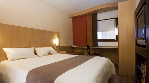 Una habitación de hotel con una cama grande, un escritorio y un televisor.