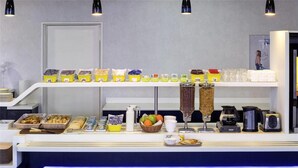 Un bufé de desayuno con diversas opciones de comida, una cafetera y un tostador.