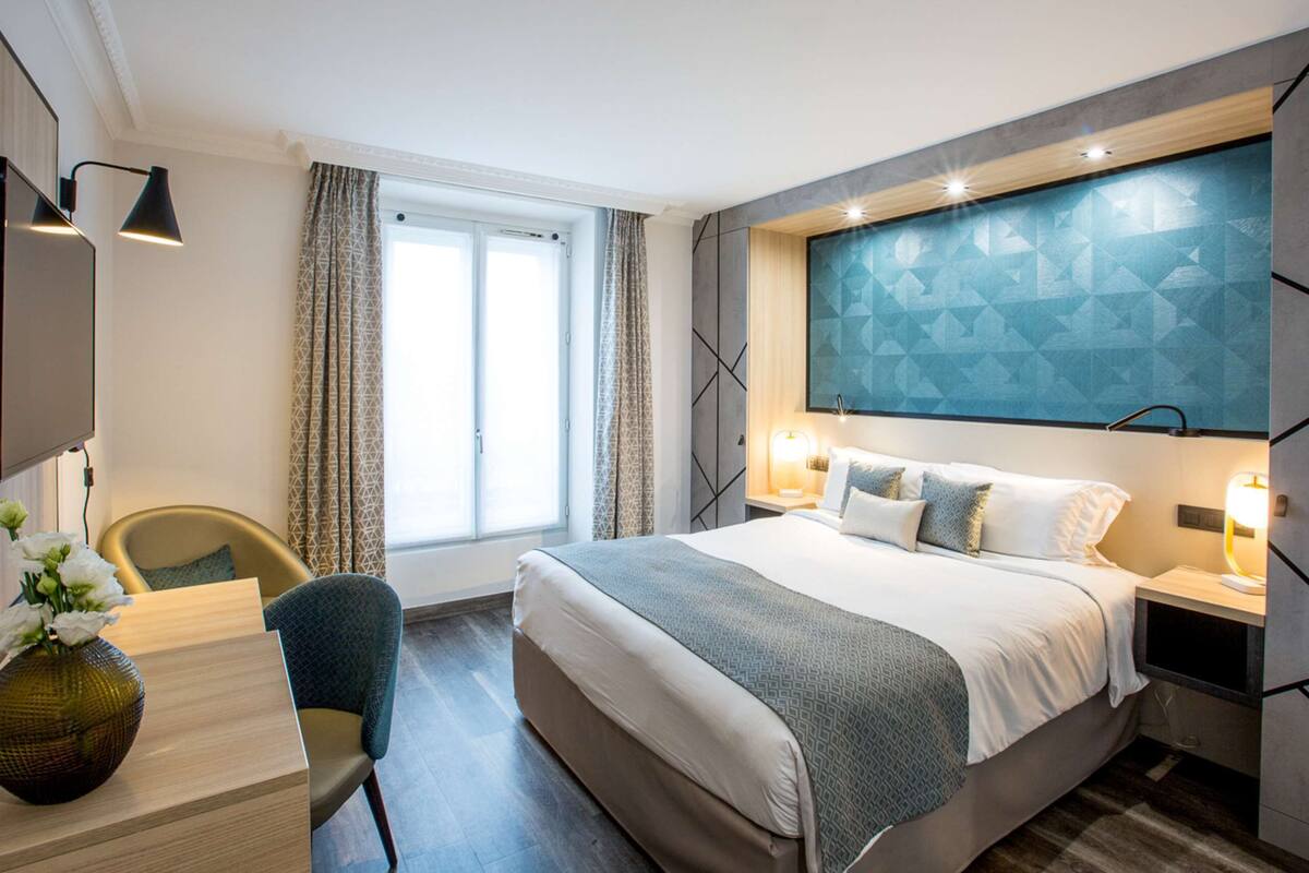 Una habitación de hotel moderna con una cama grande, un escritorio, una silla y un televisor.