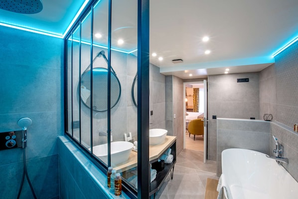 A modern bathroom with a glass shower enclosure, a large bathtub, and a vanity with a sink. - Best Western Plus Opera Batignolles (Paris)