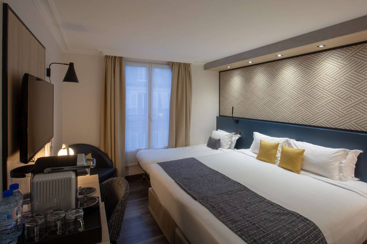 Una habitación de hotel con una cama grande, un escritorio con silla, televisión y un radiador.