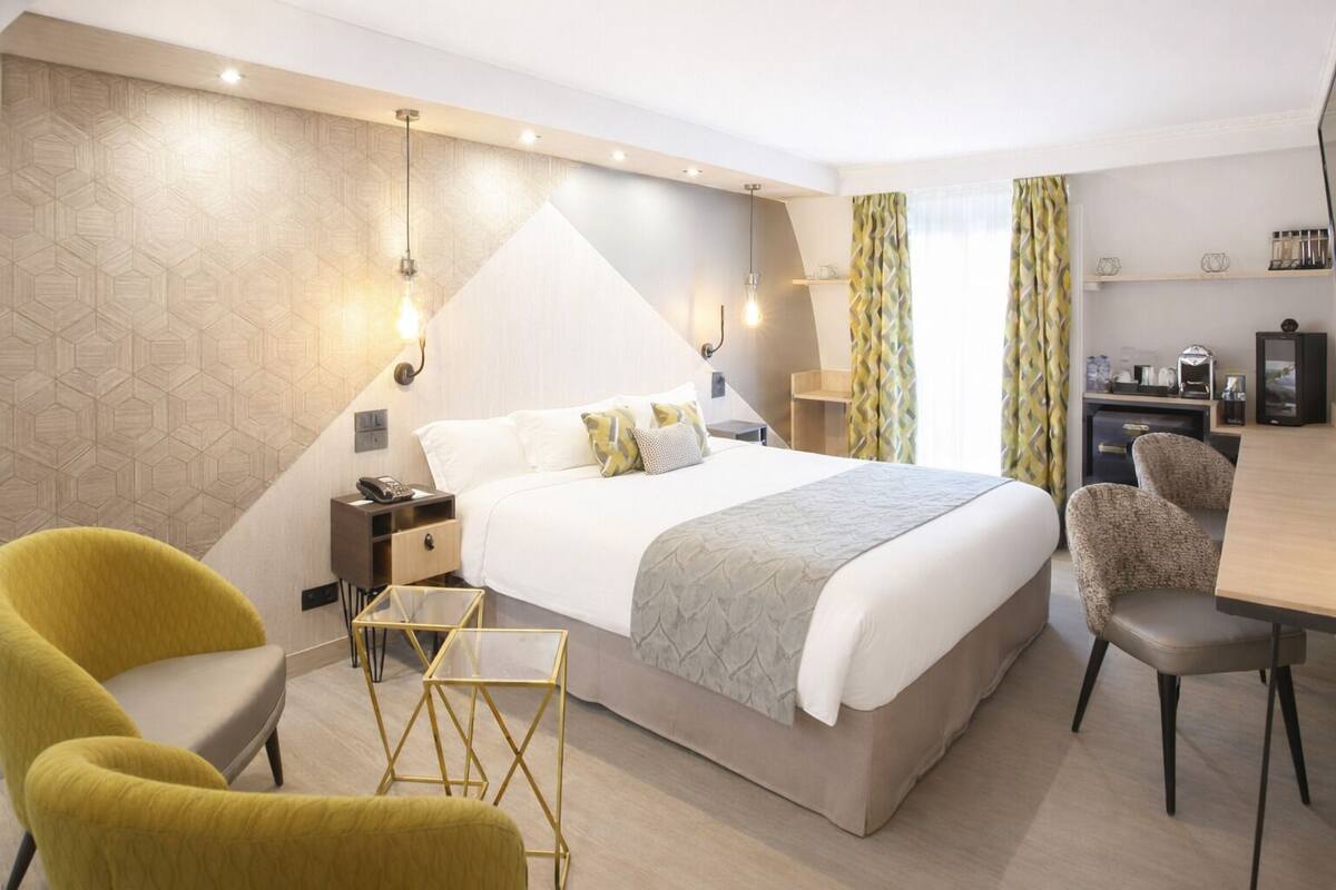 Una habitación de hotel moderna con una cama grande, un escritorio y dos sillas.
